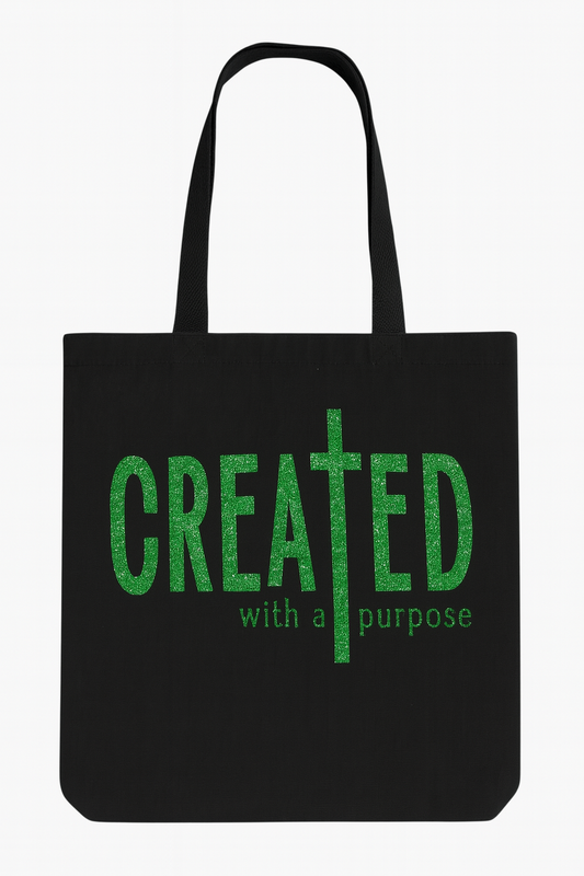Black tote bag with green text 'CREATED with a purpose' on a white background