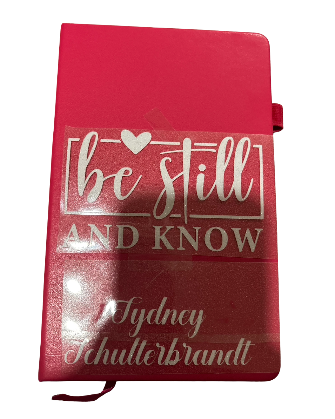 Red notebook with 'be still and know' text on a white background